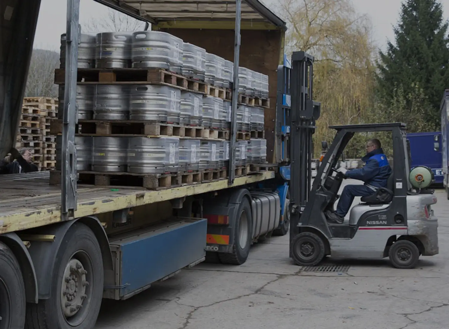 Photo d'un élévateur et un ouvrier en train de décharger les fûts de bières d'un semi-remorque.